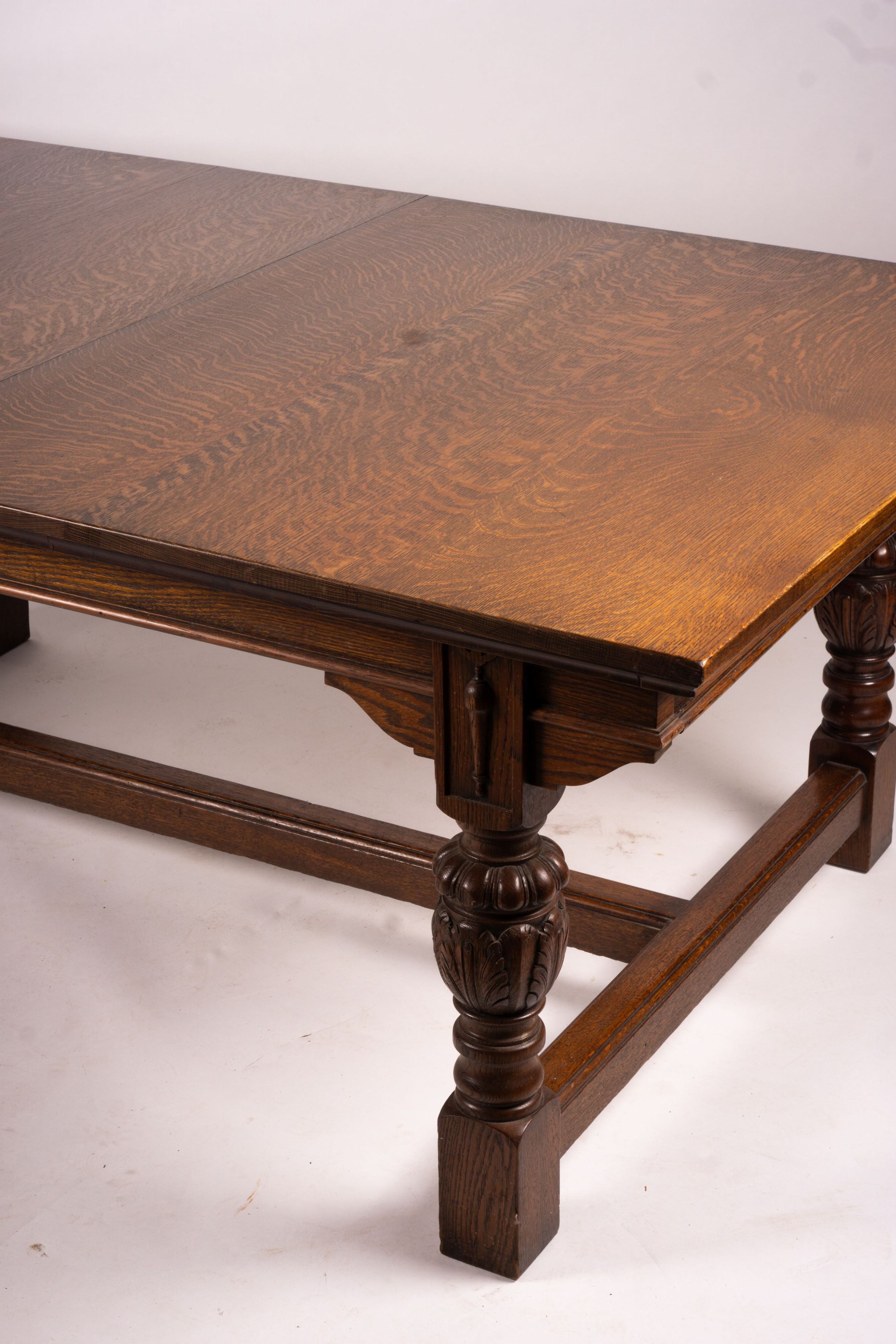 A 17th century style carved rectangular oak extending dining table with 'H' stretcher, 300cm extended, two spare leaves, width 121cm, height 75cm